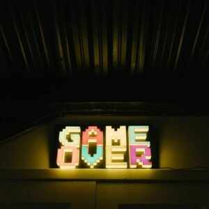 Glowing neon sign with pixelated Game Over text in a dark arcade setting.