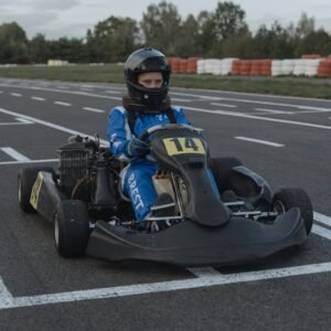 A go-kart racer ready at the starting line on an outdoor racing track during daytime.