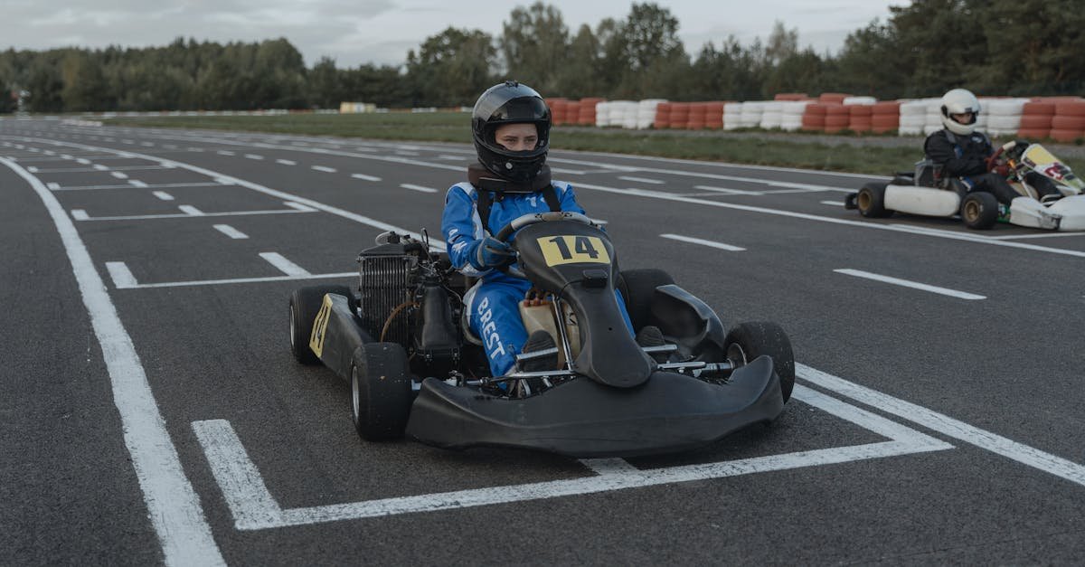 A go-kart racer ready at the starting line on an outdoor racing track during daytime.