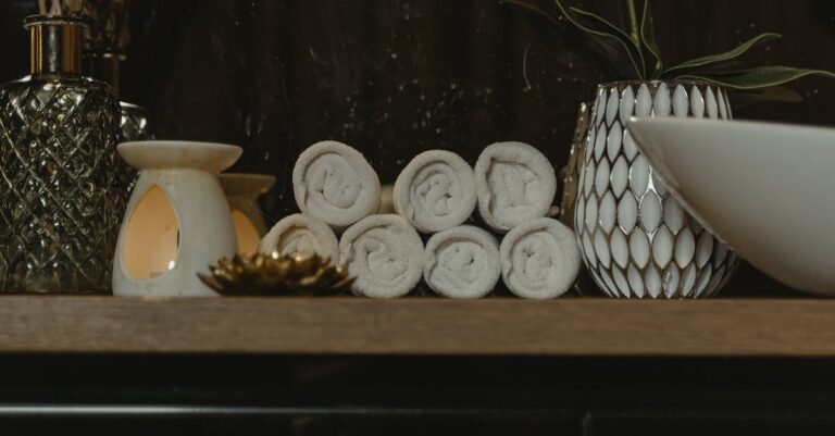 Serene spa setting featuring rolled towels, candlelight, and decorative vases on a wooden shelf.